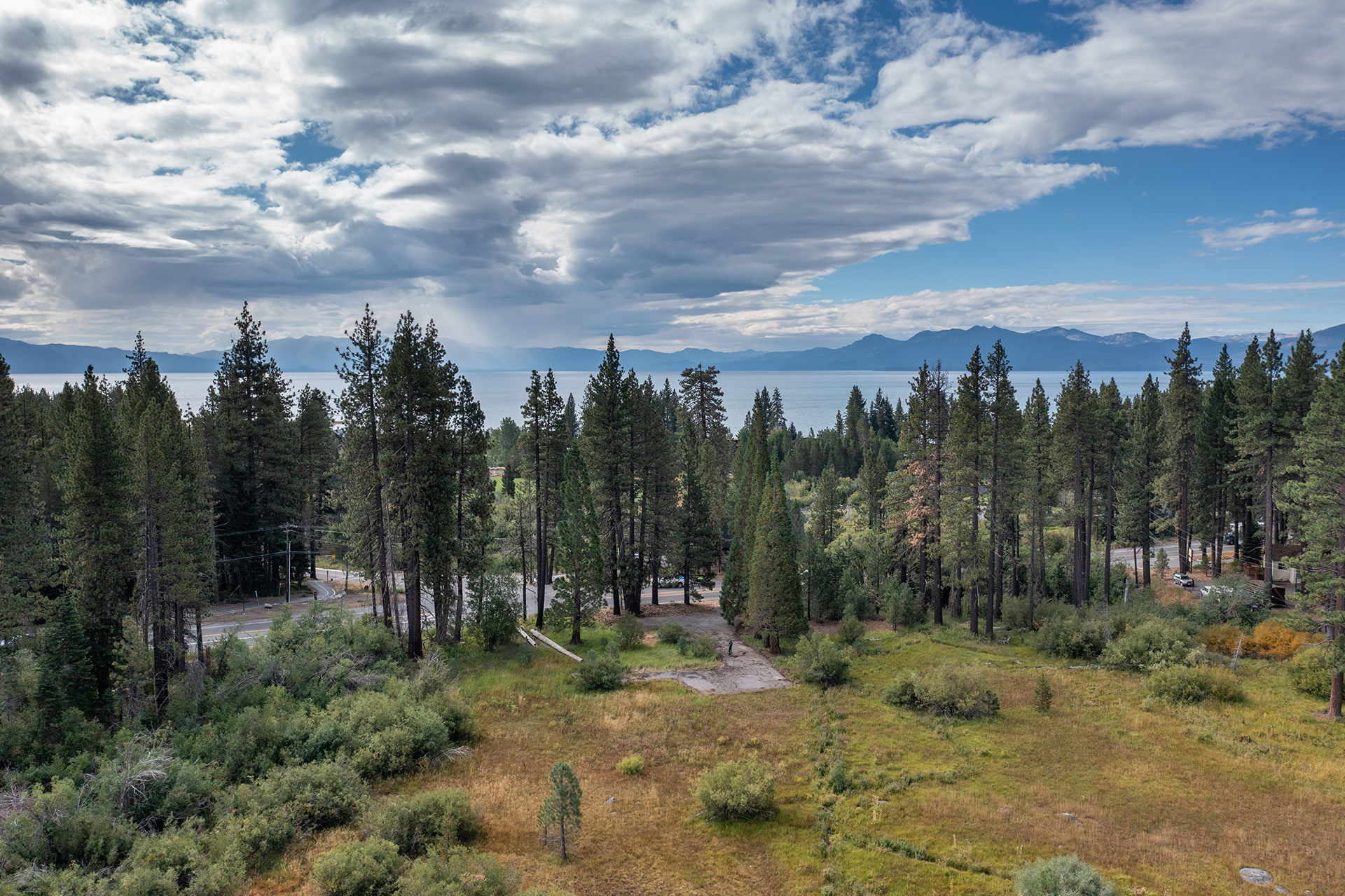 A meadow, a parking area, and lake tahoe in the background