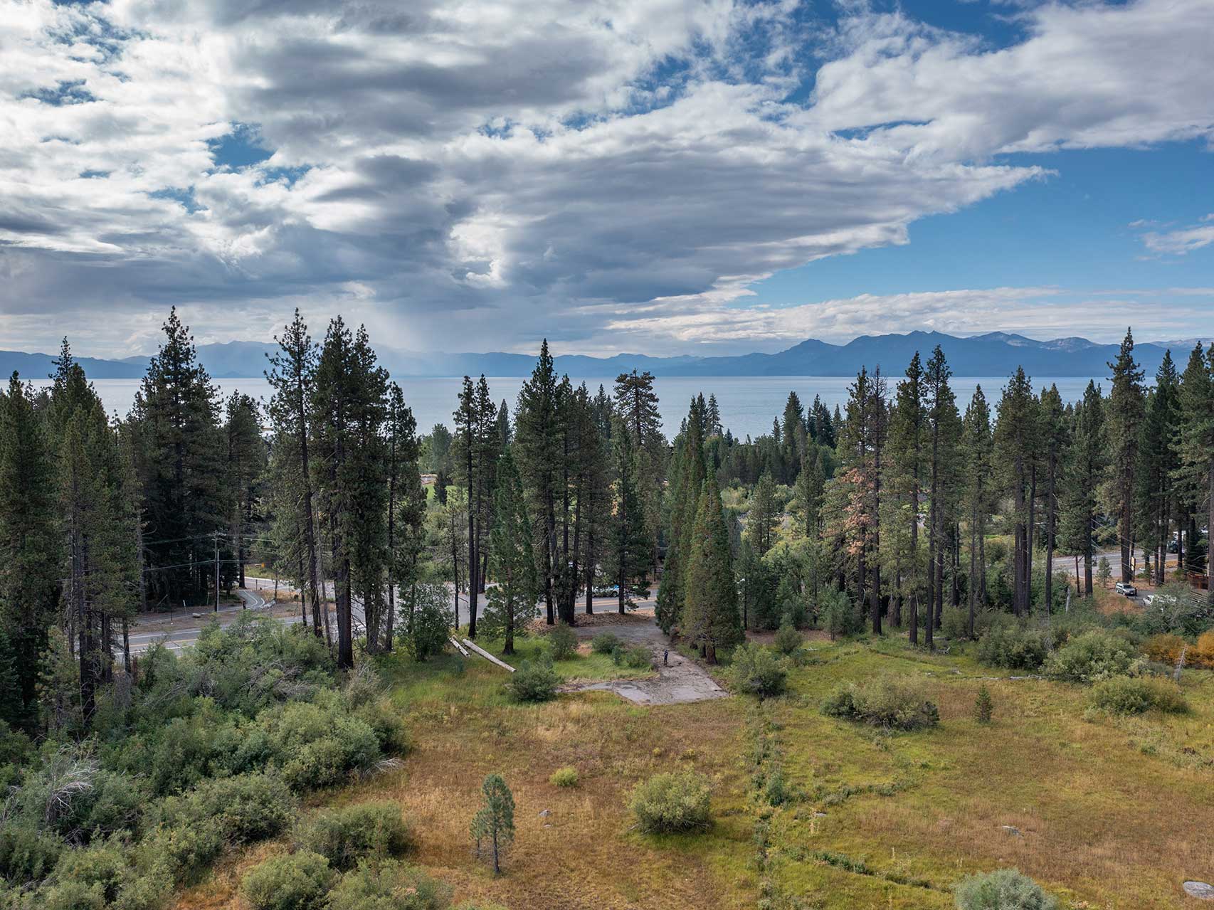 A meadow, a parking area, and lake tahoe in the background