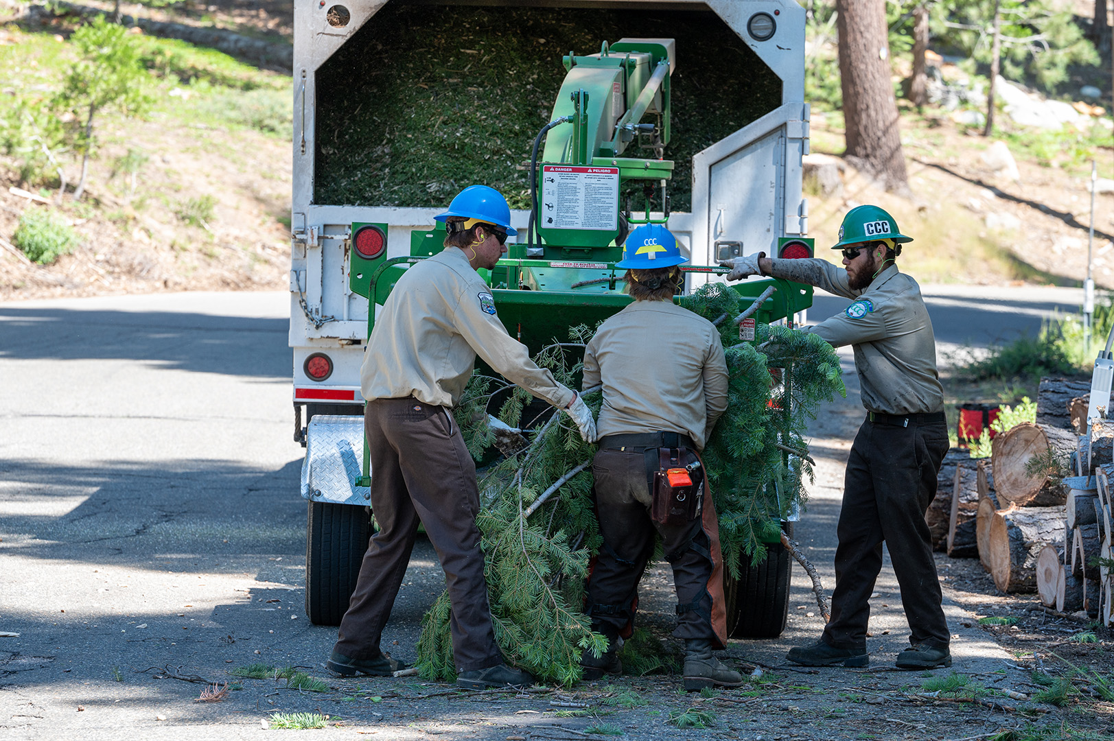 California Conservation Corpsmembers sending branches and brush from Conservancy land into a chipper.