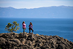 Two people standing on Eagle Rock, with Lake Tahoe in the background.