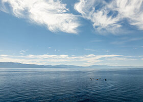 Participants in a program run by the Tahoe Waterman Foundation rowing on Lake Tahoe with mountains in the background.