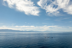 Participants in a program run by the Tahoe Waterman Foundation rowing on Lake Tahoe with mountains in the background.