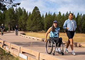 People enjoying the a section of shared use trail on a boardwalk across a meadow.